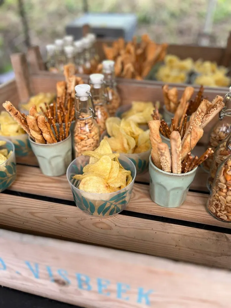 Houten krat met bakjes chips en soepstengels voor bij de borrel