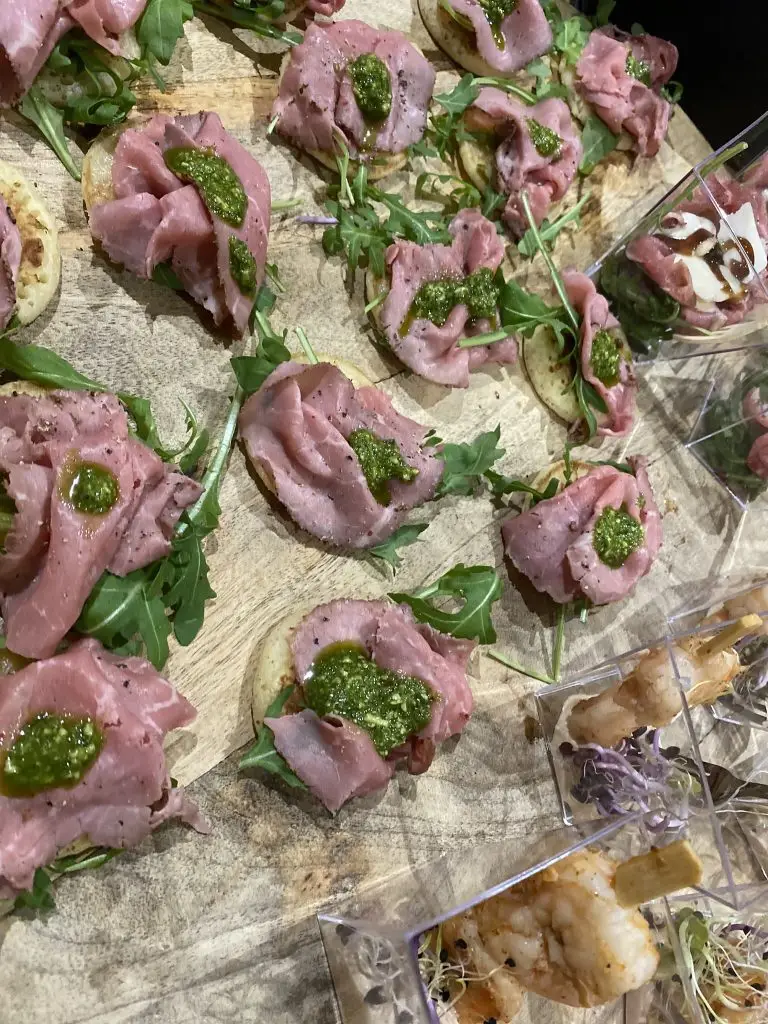 Hapjes met rosbief, pesto en rucola op een plank