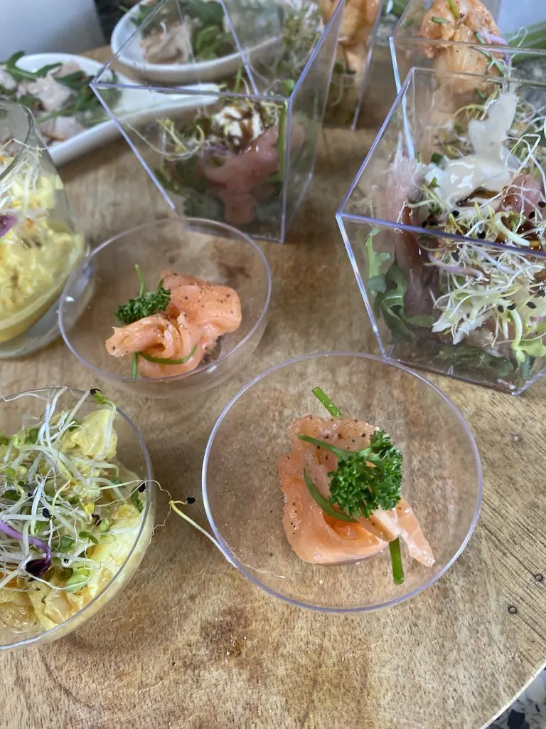Glaasjes met salades en gerookte zalm op een houten buffettafel