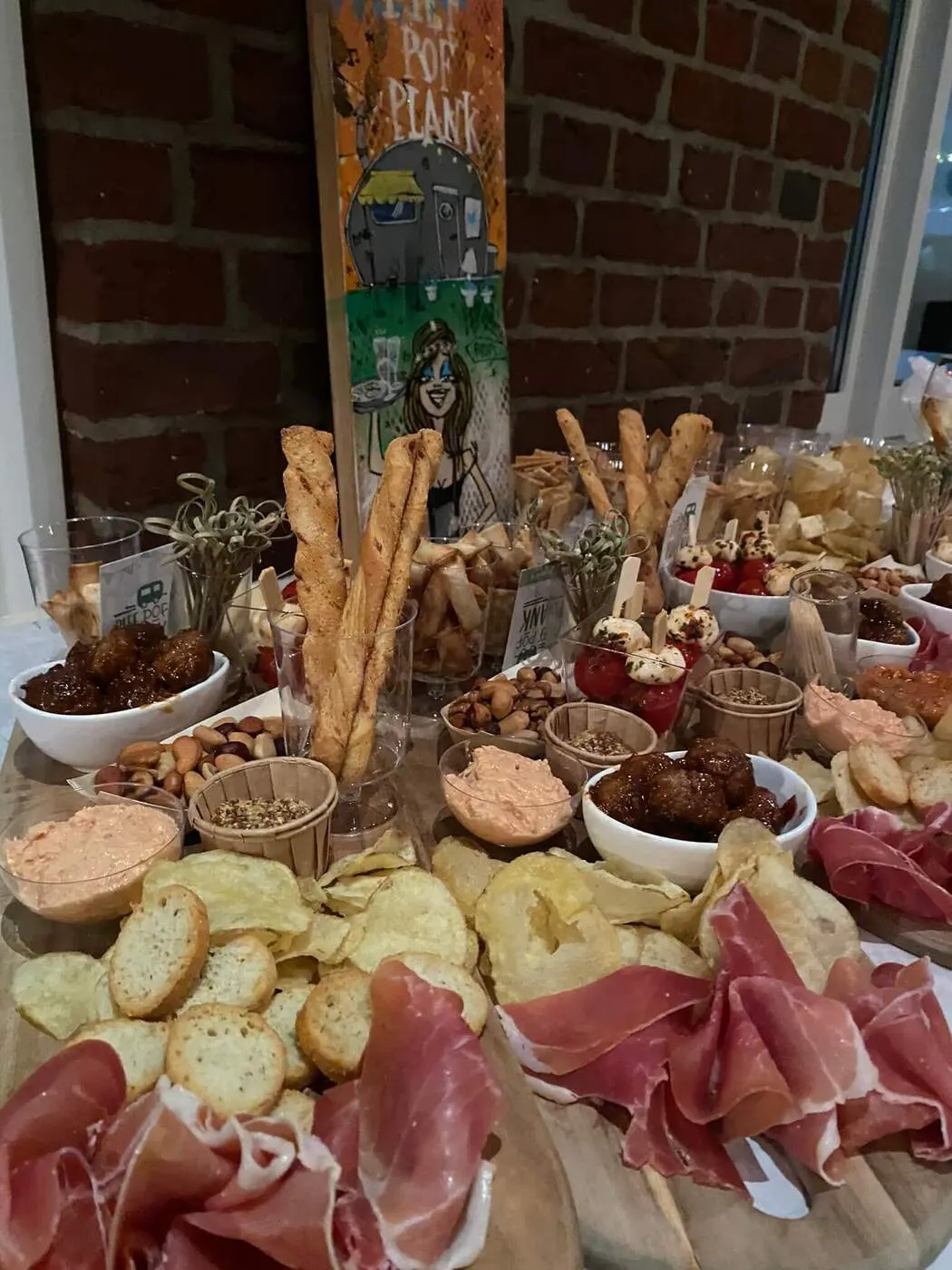Borrelplank met ham, kaas en soesjes tegen een bakstenen muur