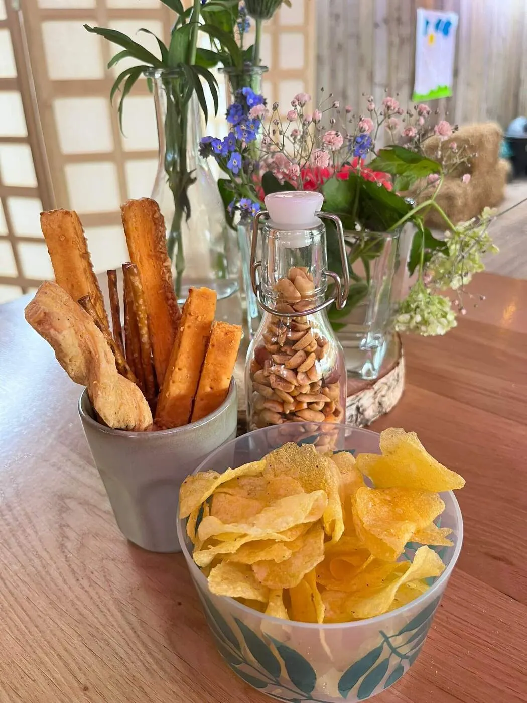 Chips en soepstengels tussen verse bloemen op tafel