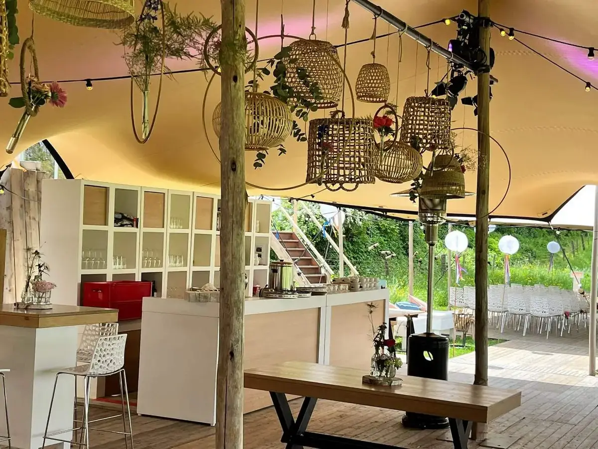 Feesttent met bar en hangende mandjes, ingericht voor een event